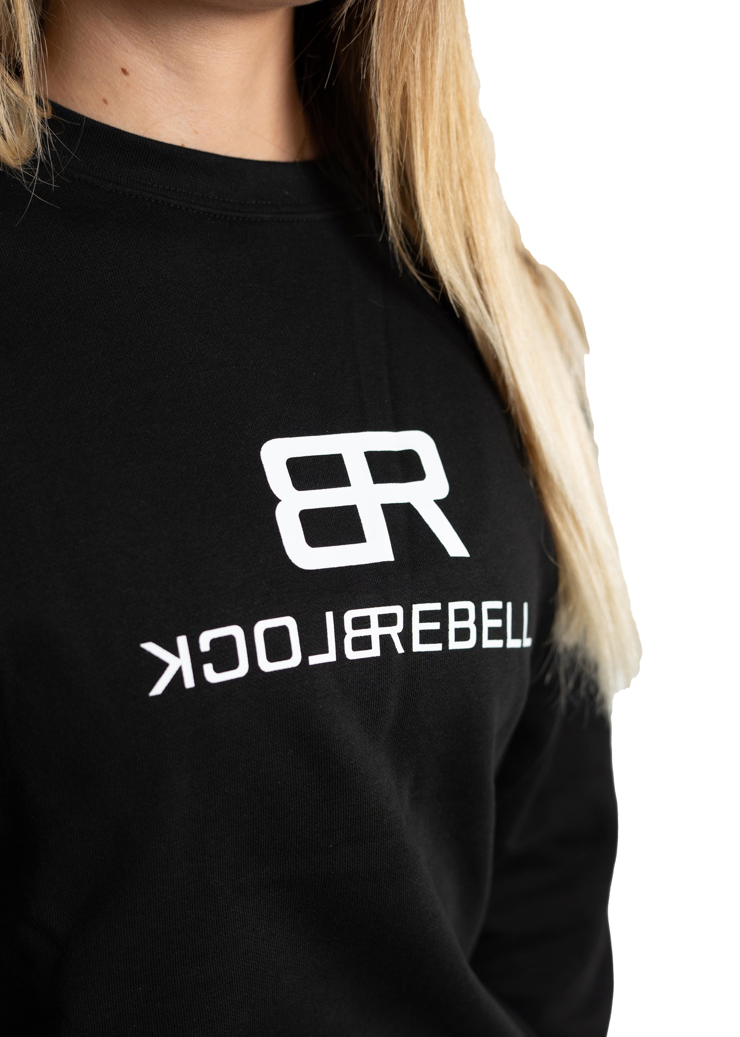 Frau trägt schwarzen Rebell Sweater und Jogger von BlockRebell – sportlich-lässiger Look auf weißem Hintergrund