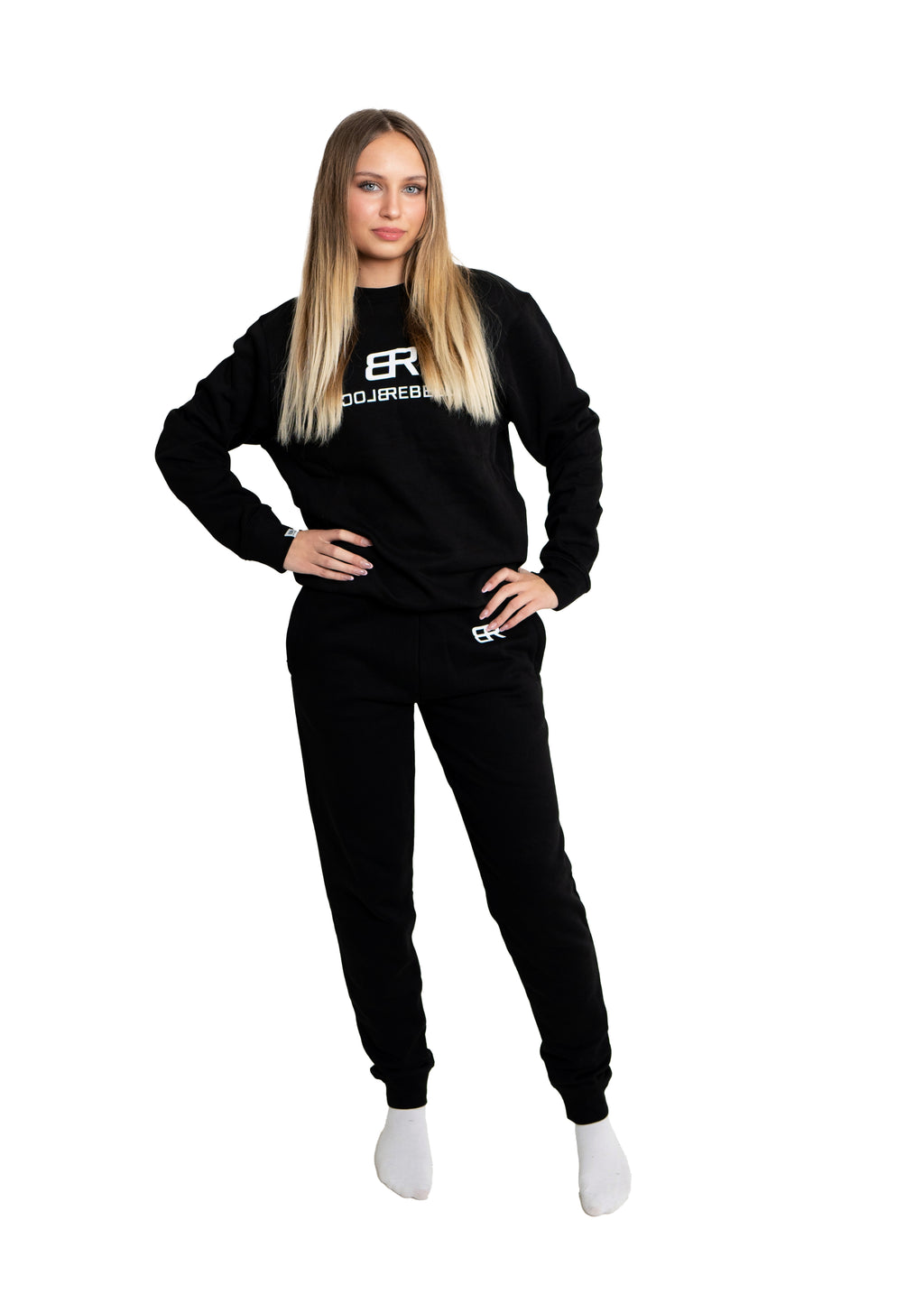 Frau trägt schwarzen Rebell Sweater und Jogger von BlockRebell – sportlich-lässiger Look auf weißem Hintergrund