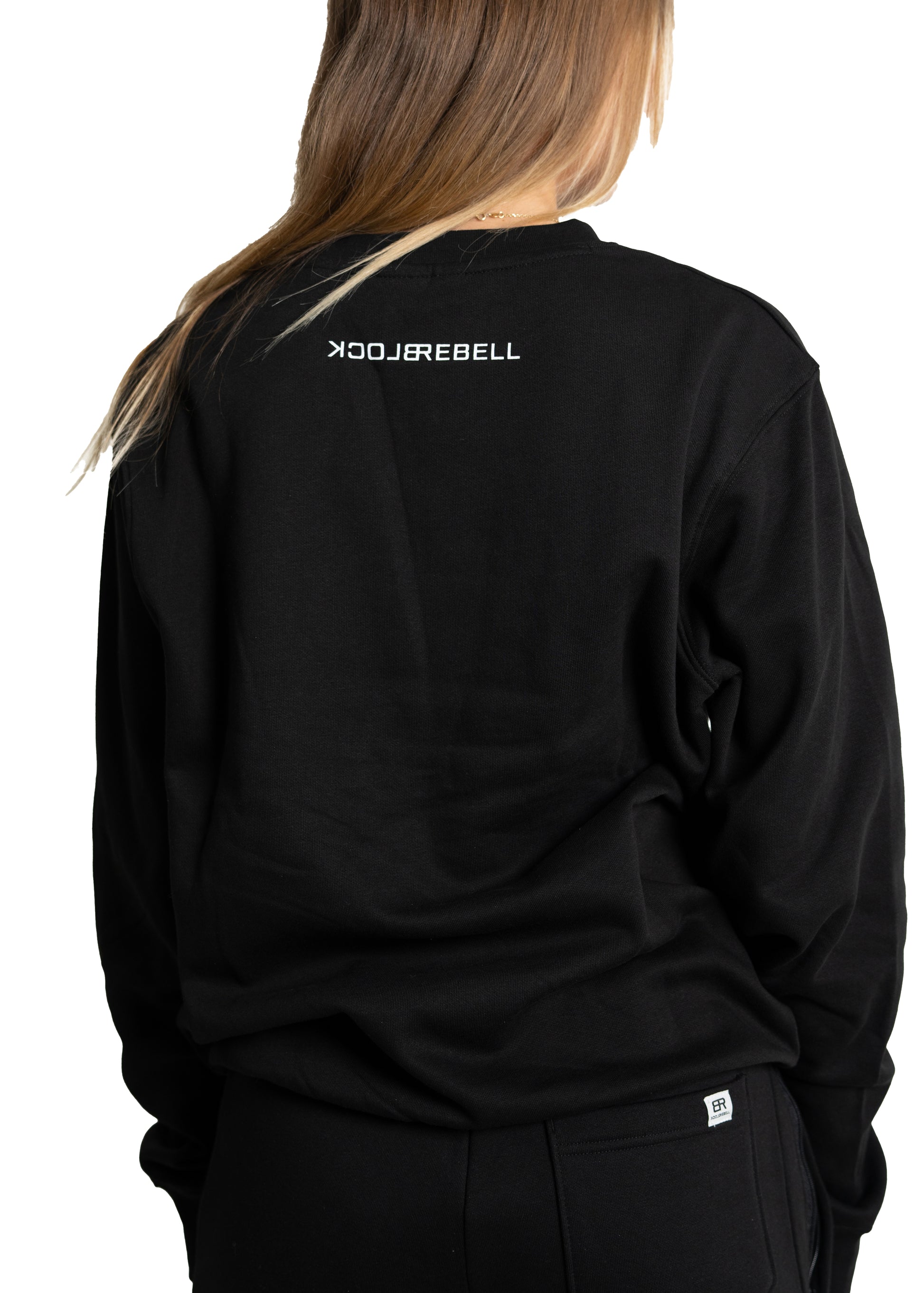 Frau trägt schwarzen Rebell Sweater und Jogger von BlockRebell – sportlich-lässiger Look auf weißem Hintergrund