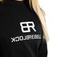 Frau trägt schwarzen Rebell Sweater und Jogger von BlockRebell – sportlich-lässiger Look auf weißem Hintergrund