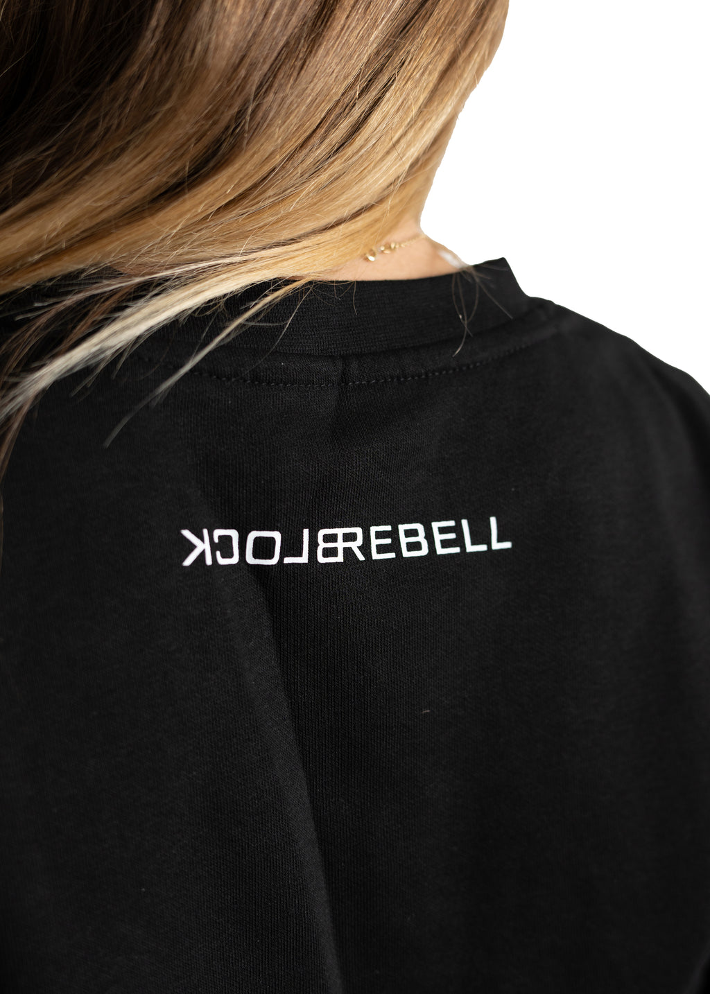 Frau trägt schwarzen Rebell Sweater und Jogger von BlockRebell – sportlich-lässiger Look auf weißem Hintergrund