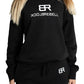 Frau trägt schwarzen Rebell Sweater und Jogger von BlockRebell – sportlich-lässiger Look auf weißem Hintergrund