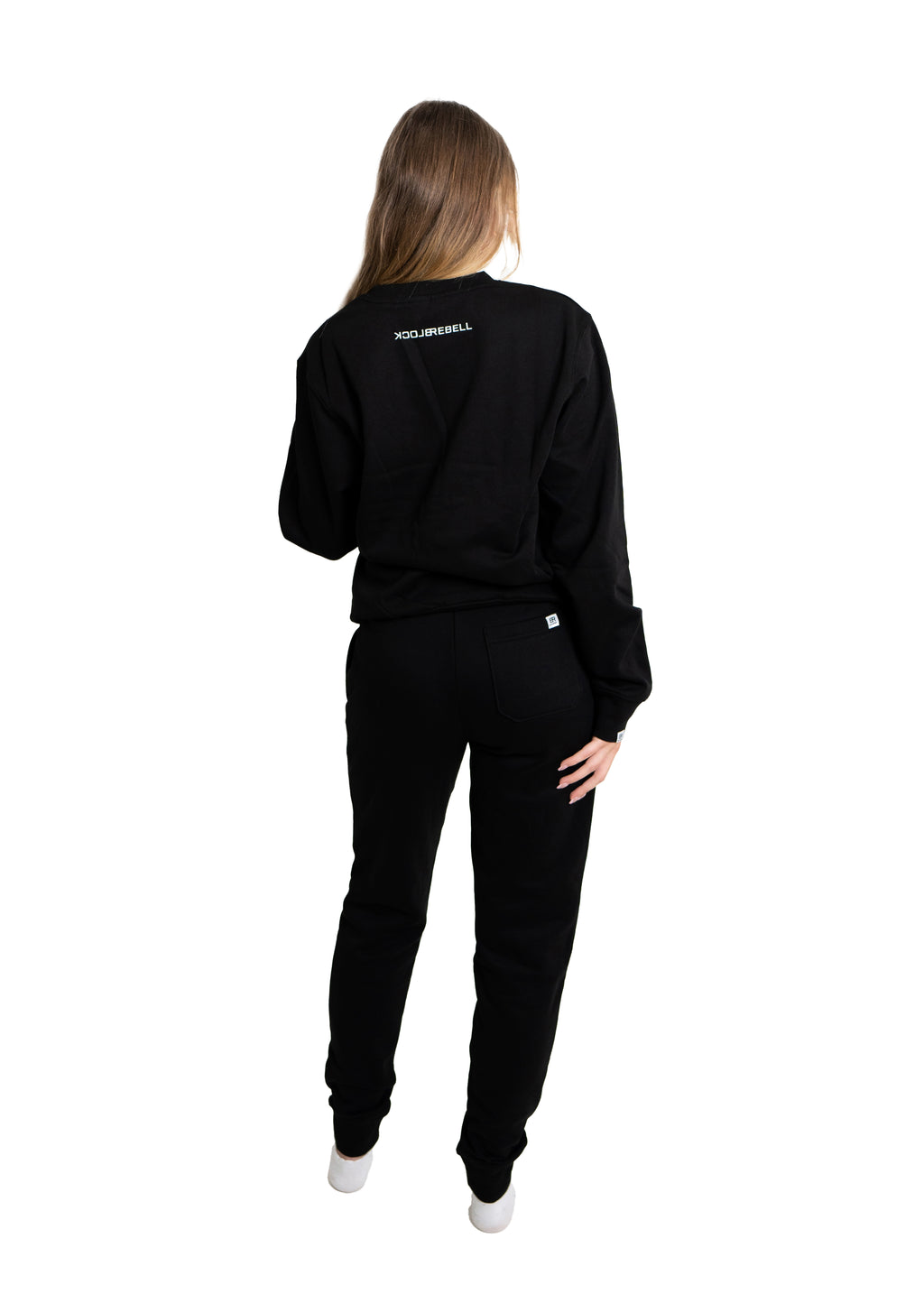 Frau trägt schwarzen Rebell Sweater und Jogger von BlockRebell – sportlich-lässiger Look auf weißem Hintergrund